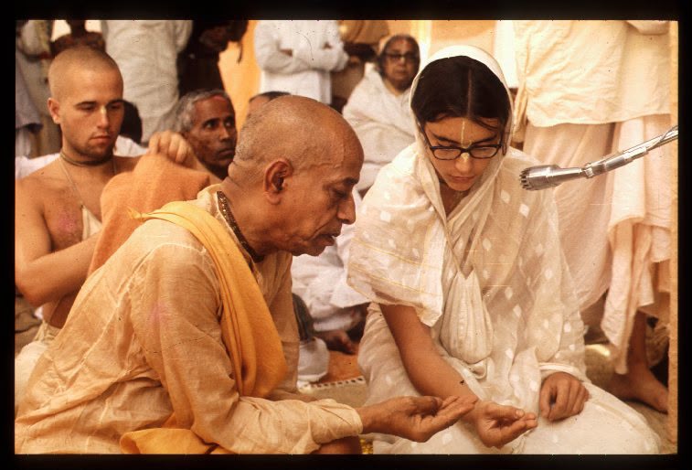 Srila Prabhupada seated beside a woman at a ceremony